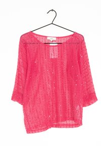Haut en maille rose à manches trois-quarts, présentant une coupe ample et de subtils accents de sequins. Suspendu sur un crochet noir contre un fond blanc.