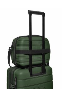 Groene harde koffer set met textuur, inclusief een koffertje op wielen met een uittrekbare handgreep en een kleinere tas die bovenop is bevestigd.