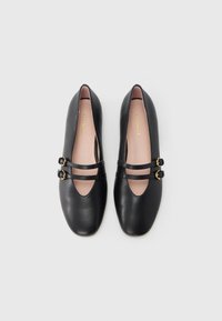 Μαύρα μπαλαρίνες από δέρμα με στρογγυλεμένη μύτη, δύο στενές λουρίδες, χρυσά μεταλλικά διακοσμητικά και ομαλή ροζ εσωτερική σόλα.