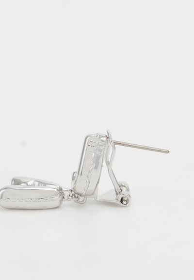 Silberohrringe mit glänzender Oberfläche, die ein einzigartiges Design aufweisen, das an ein Schloss erinnert, mit einer geraden Stiftbefestigung. Sichtbare strukturierte Akzente.