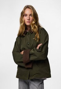 Olivaroheline jakk pruuni sametist krae ja mansettidega, nupuga kinnitamine ja mugav lõige. Tekstuuriga kangas ja minimalistik disain.