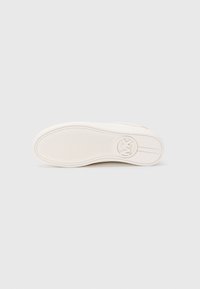 White sneaker sole with textured grip and circular logo near the heel, shown against a plain white background.