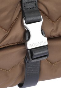 Borsa in tessuto trapuntato marrone con tracolla in pelle nera, caratterizzata da una fibbia in metallo argentato con incisione "BOGNER". Visibili dettagli cuciti.