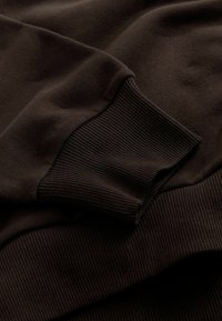 Sötétszürke pulóver anyag bordás mandzsetta részletekkel. Sima textúrájú, laza fit, tiszta vonalakkal és minimalista dizájnnal.