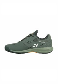 Green athletic shoe with a smooth upper, ventilated side panels, and durable rubber sole featuring an orange accent in the heel area.
