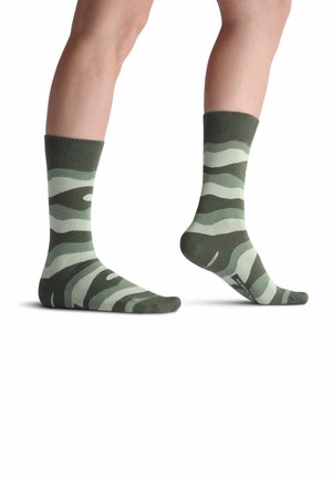 Calcetines a rayas verdes y verde claro con un puño acanalado, de longitud medio-calcetín y una textura suave. Presentan un logo en la suela.