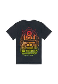 T-shirt en coton noir avec un texte graphique vibrant en orange, jaune et vert au dos. Le design comprend des accents de fil barbelé et un logo.