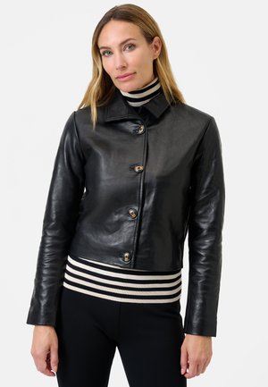 Black leather jacket featuring a collared neckline, front buttons, and a cropped design, paired with a striped sweater underneath.
