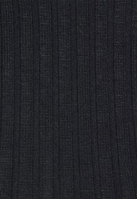 Gros plan d’un tissu tricoté côtelé noir avec des rayures verticales texturées et une surface légèrement rugueuse.