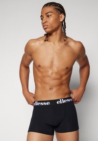 Black boxer briefs with a white "ellesse" logo on the waistband. The fabric appears smooth and fitted, highlighting body contours.