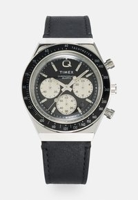 Montre chronographe Timex avec un bracelet en cuir noir, un boîtier en acier inoxydable argenté, un cadran noir, trois sous-cadrans et une échelle tachymétrique.
