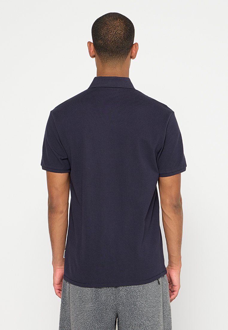 Polo bleu marine, manches courtes, col, et ourlet droit. Fabriqué en tissu coton texturé, avec une coupe décontractée.