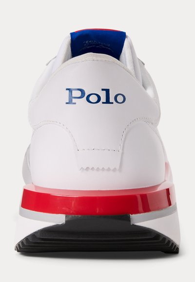 Sapatilha atlética branca com o logo azul "Polo" no calcanhar, detalhe em vermelho na sola, textura de couro suave e um colarinho almofadado.