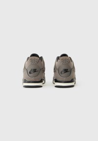 Nike tenisice s gornjim dijelom od sivo antilop kože, crnim detaljima i bijelim potplatom. Imaju podstavljeni ovratnik i istaknutu potpisnu oznaku na peti.