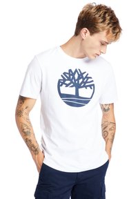 Weißes Baumwoll-T-Shirt mit einem großen navyblauen Baum-Logo. Das Shirt hat einen Rundhalsausschnitt und kurze Ärmel; glatte Textur.