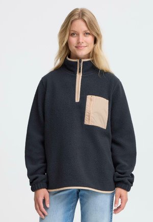 Sort fleece pullover med halv-zip top, beige lynlås trim og en beige brystlomme. Features et tekstureret stof og elastiske manchetter.