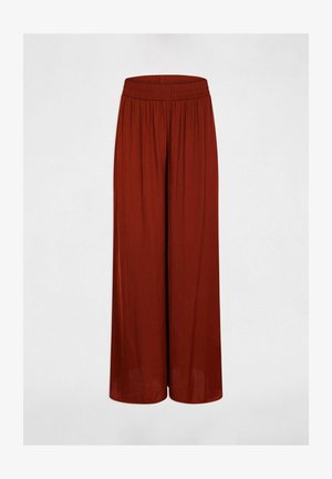 Pantaloni a gamba larga di colore ruggine con vita elasticizzata arricciata, mostrati su sfondo chiaro e uniforme.