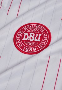 Red and white Danish Football Union emblem on white fabric with thin vertical red and gray stripes.