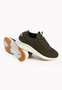 Olivgrüne gestrickte Sneakers mit weißen Gummisohlen und hellbraunen Lederelementen. Verfügt über eine strukturierte Oberseite und ein Schnürdesign.