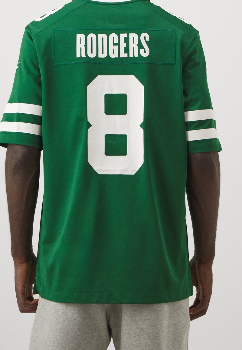 Personne portant un maillot de sport vert avec des rayures blanches et "RODGERS" ainsi que le numéro 8 dans le dos, assorti d'un short gris.