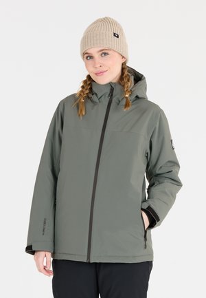 Grüne wasserdichte Jacke mit Reißverschluss, verstellbare Kapuze und zwei seitlichen Taschen. Getragen mit einer beigen gestrickten Mütze. Glatte Textur.
