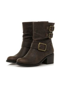 Stivaletti in pelle marrone con tre fibbie in ottone e un tacco basso, su uno sfondo bianco.