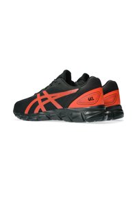 Scarpe da ginnastica nere con dettagli rossi, dotate di una tomaia in mesh, un'intersuola testurizzata e una suola in gomma. Caratteristica stampa GEL sul tallone.