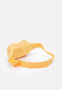 Žlutý nylonový ledvinka s zakřiveným tvarem, dvěma kapsami na zip a nastavitelným popruhem se plastovou sponou.