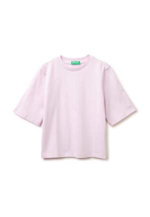 Camiseta de algodón rosa claro de manga corta con cuello redondo y una etiqueta verde en el interior del cuello, mostrada sobre un fondo blanco.
