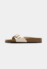 Sandale slide beige unique avec semelle intérieure en liège et semelle extérieure noire texturée, équipée d'une bride réglable avec une boucle en or rose.