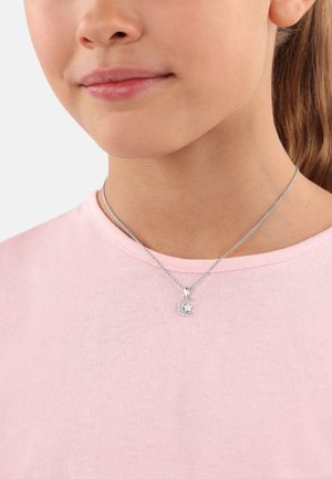 Silberne Halskette mit einem Anhänger in Form eines Halbmonds und einem Sternelement, getragen über einem hellrosa T-Shirt mit rundem Ausschnitt.