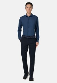 Marineblauwe langesleeve knopenhemd gecombineerd met donkere broek en een gestructureerde riem, met een nette kraag en een Slim fit ontwerp.