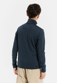 Maglietta a maniche lunghe blu navy con colletto alto, realizzata in tessuto morbido, con una vestibilità slim e un piccolo etichetta logo sull'orlo.
