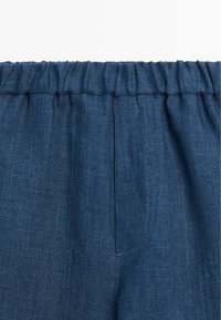 Pantalon en lin bleu foncé avec une taille élastique et des coutures visibles sur la couture centrale avant.