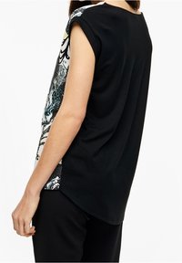 Top corto nero a maniche corte con un lato decorato in blu, bianco e nero. Tessuto morbido con una vestibilità comoda, caratterizzato da un orlo arrotondato e fessure laterali.
