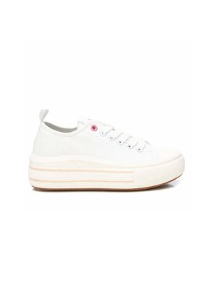 Zapatilla blanca de lona de corte bajo con suela gruesa, seis ojales para cordones, un ojal rosa cerca del tobillo y una lengüeta en el talón.