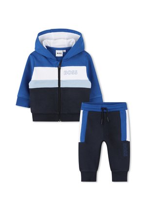 Ensemble de survêtement à capuche en bleu, blanc et marine. Comprend une fermeture zippée, des poches latérales et des blocs de couleur contrastés sur la veste et le pantalon.