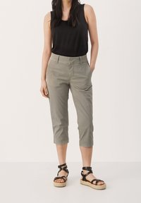 Světle šedé zkrácené chino kalhoty s předními kapsami, poutky na opasek a slim fit, spárované s černými espadrilky a černým tílkem.