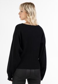 Maglione nero realizzato in materiale morbido, con una vestibilità rilassata, maniche ampie e orlo a coste in vita.