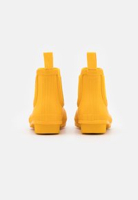 Κίτρινα λάστιχα μποτάκια αστραγάλου με ριμπέ μεταξωτή υφή, ενισχυμένη φτέρνα και λαβές για εύκολη χρήση. Μαλακή επιφάνεια με επίπεδη, ανθεκτική σόλα.