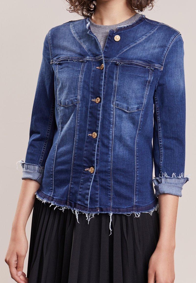 Jeansjacka i mörkblått med knäppning fram, två bröstfickor, uppvikta ärmar och fransad fåll. Tillverkad av bomull, avslappnad design.