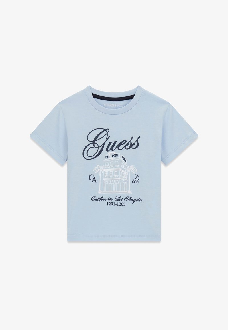 Chemise à manches courtes bleu clair avec logo "Guess", illustration de bâtiment, palmiers et texte "California, Los Angeles 1201-1203" sur le devant.