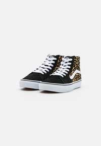 Svarta och leopardmönstrade höga sneakers med vita snören, en gummisula och kontrasterande svarta och vita designinslag.