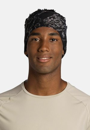 Smiling man wearing a light beige shirt and a black patterned headband with the Buff logo on a plain light background.