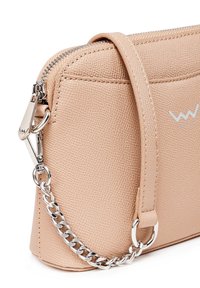 Kabelka z imitace kůže s broskvovou texturou, se stříbrným řetízkem a jemným detailem loga. Obsahuje zipový uzávěr a hladké kožené akcenty.