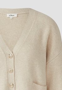 Beige gebreide cardigan met een V-hals, afgewerkt met drie metalen knopen, geribde manchetten en een voork pocket. Zachte textuur en casual ontwerp.