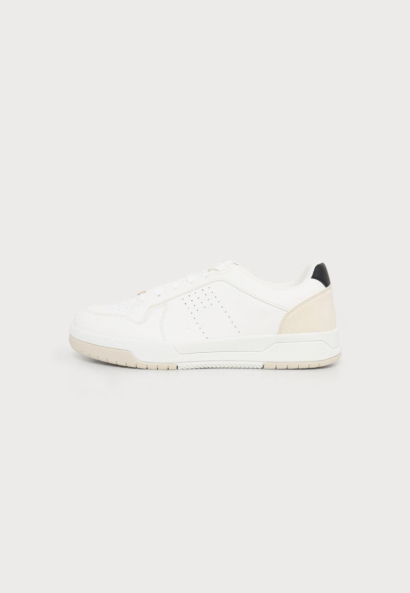 Baskets basses blanches avec semelle beige et détail au talon, design à lacets et petites lignes perforées sur le côté, vues de profil.