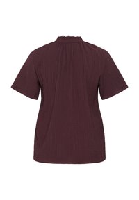 Maroon short-sleeve blouse with a textured, ribbed fabric and a high neck. Features a loose fit and side slits for comfort.