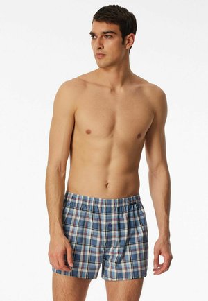 Plaid men's boxer shorts feature a blue, red, and white color scheme. Made of lightweight fabric with an elastic waistband and button detail.