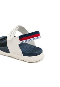 Sandalo bianco e navy con sottopiede testurizzato, cinturino in velcro e accenti a righe navy, rosso e bianco sul cinturino. Suola in gomma.